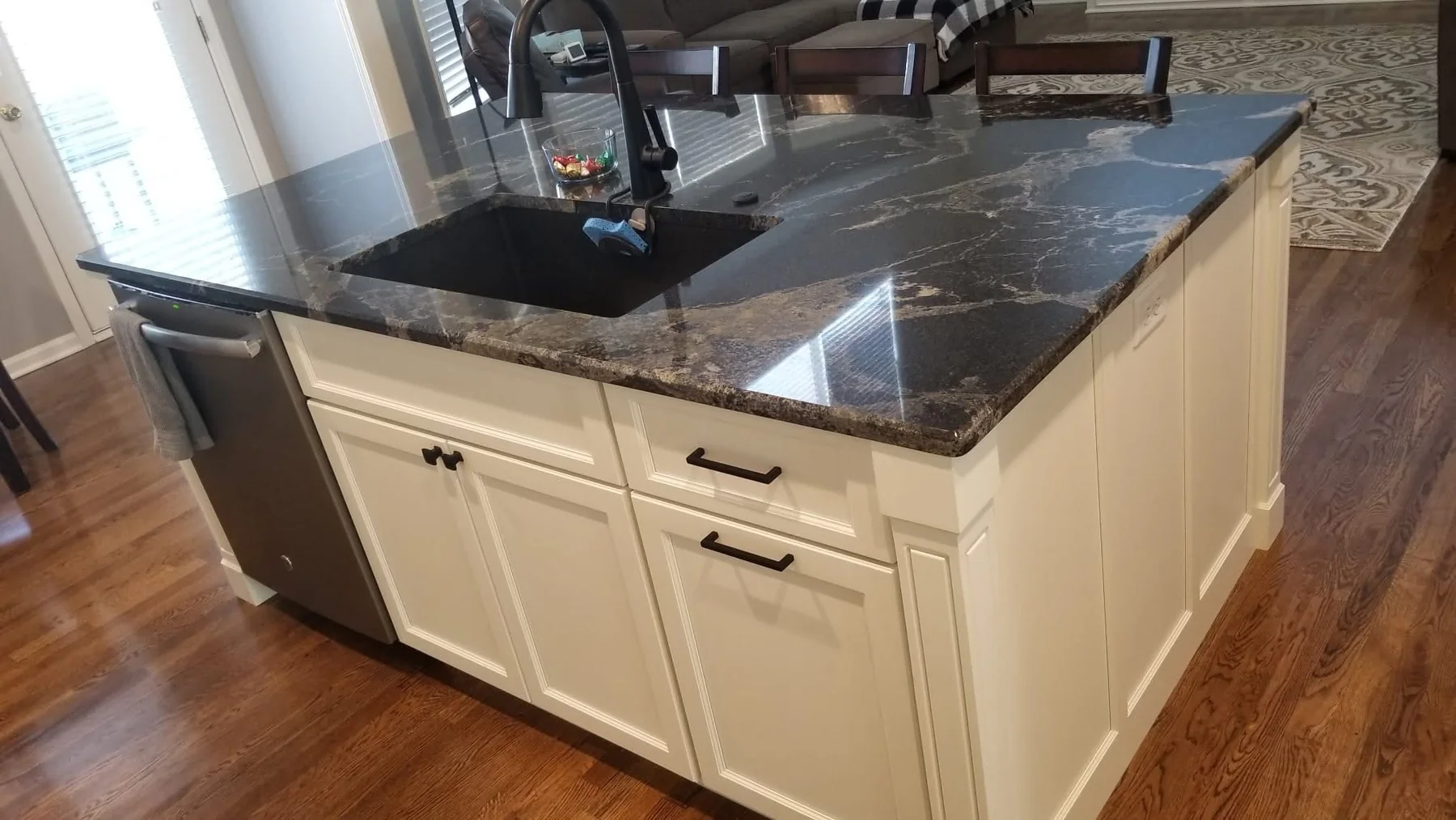 Black granite island with white cabinets installed in a Kansas City kitchen